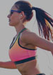 running woman with headphones in pink sports bra